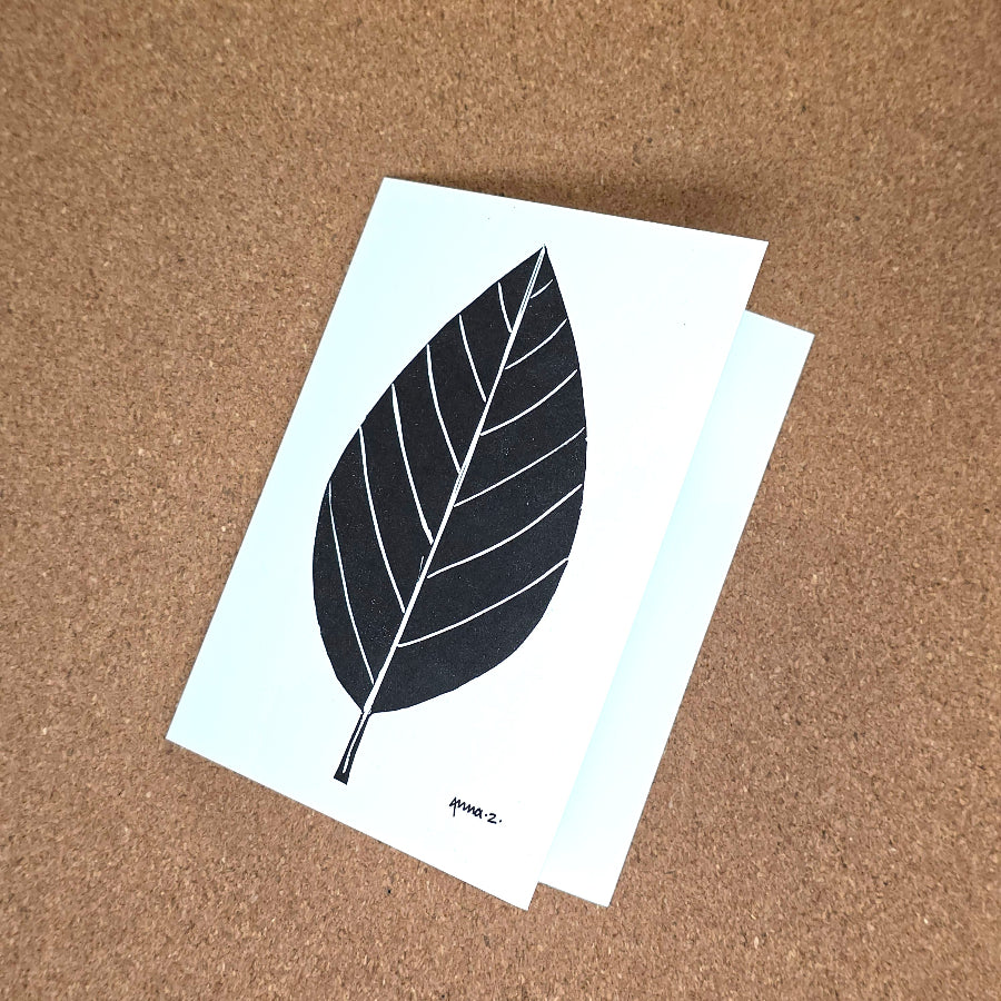 Notecard featuring a digital print reproduction of an original hand-carved block print artwork of a vertical leaf. Black and white artwork.