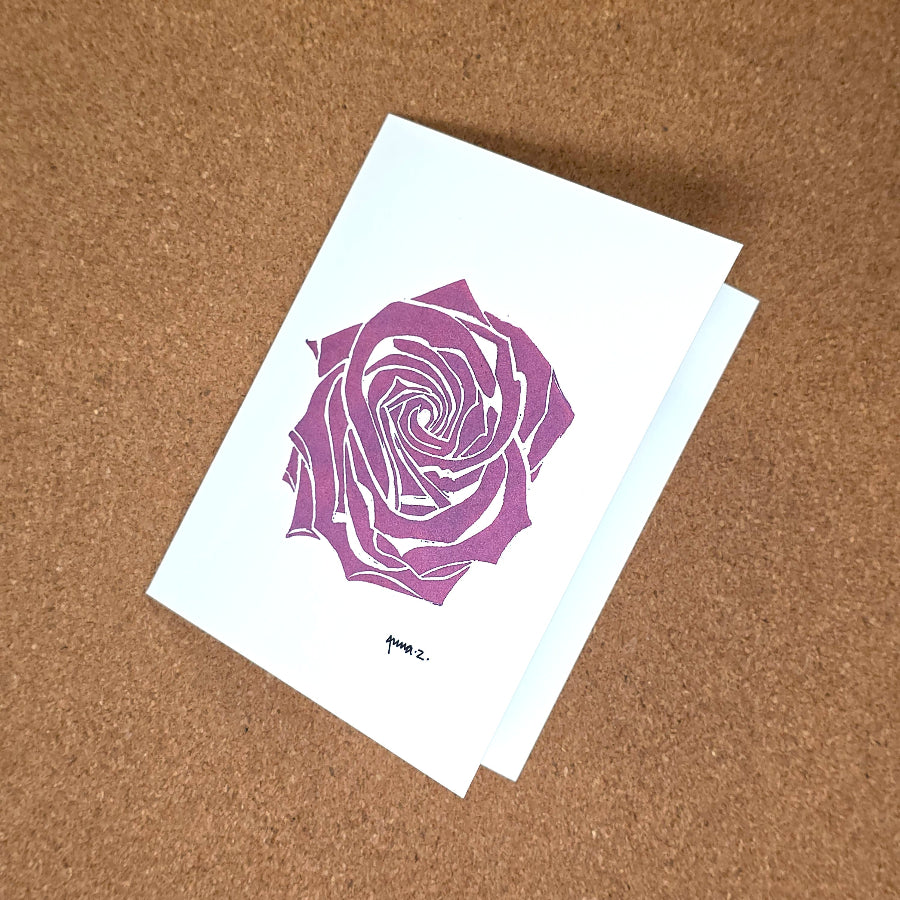 Notecard featuring a digital print reproduction of an original hand-carved block print artwork of a rose in deep pink on a white background.
