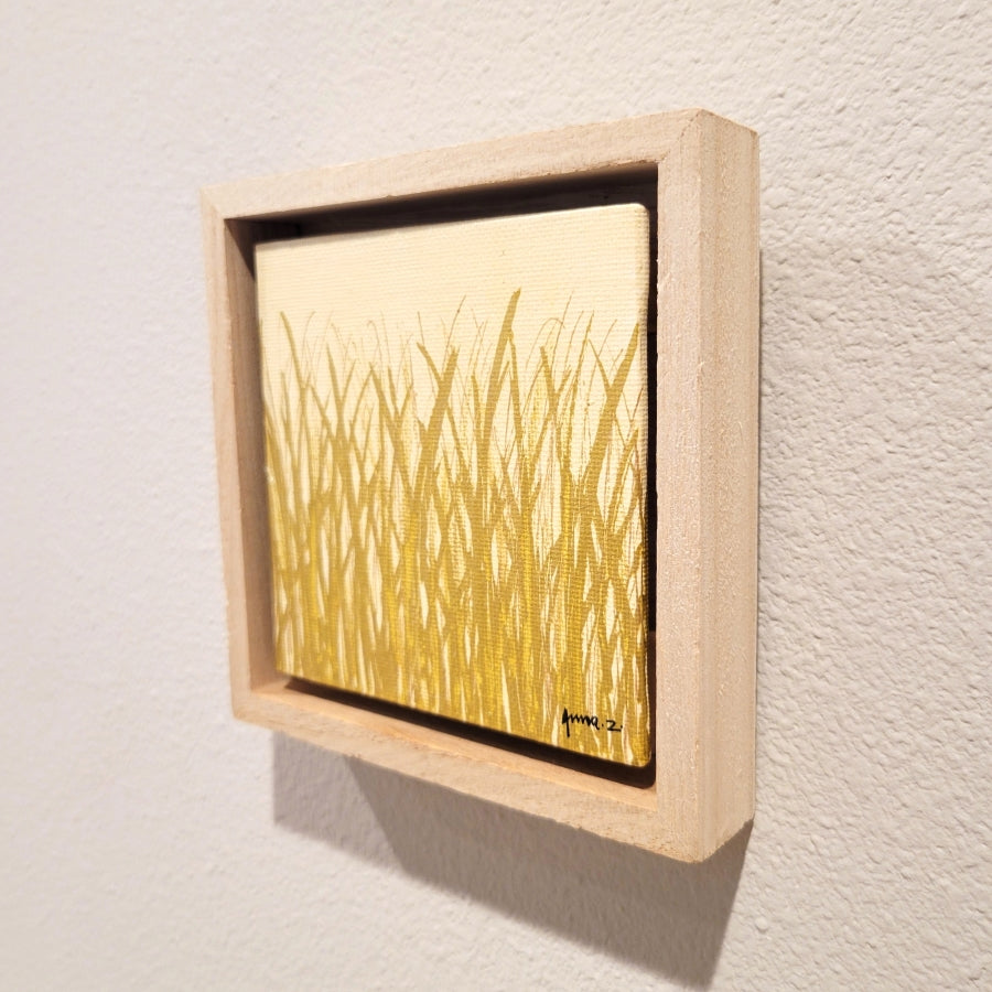 Golden blades of grass set against a cream background on a framed mini-sized canvas panel. Metallic gold colored paint over acrylic. Mounted in floater frame style within a 5" x 5" rustic wooden box frame with mini sawtooth hanger on reverse. The golden grass catches daylight beautifully and is perfectly complemented by the light colored wooden frame.