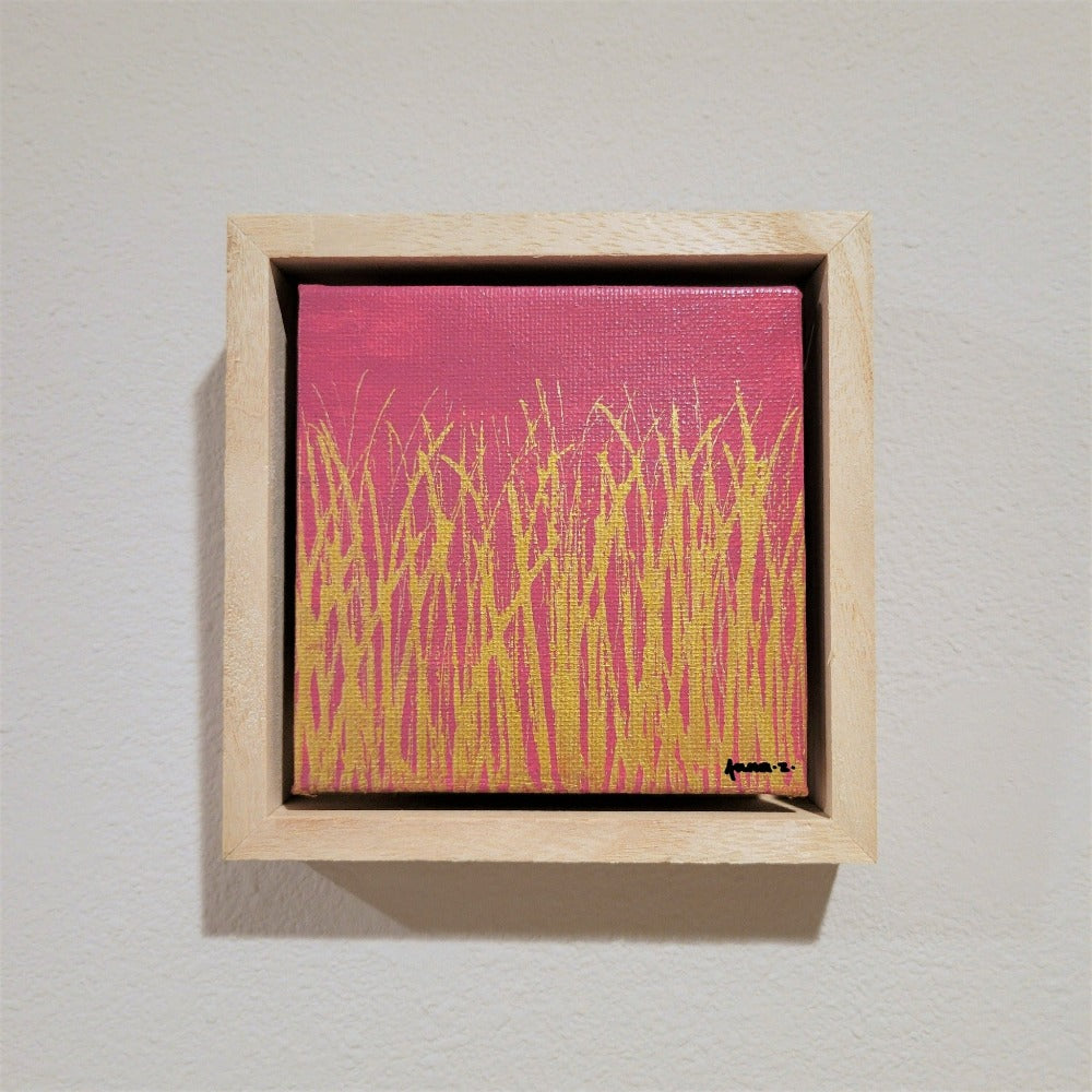 Golden blades of grass set against a bright pink background on a framed mini-sized canvas panel. Metallic gold colored paint over acrylic. Mounted in floater frame style within a 5" x 5" rustic wooden box frame with mini sawtooth hanger on reverse. The golden grass catches daylight beautifully and is perfectly complemented by the light colored wooden frame.
