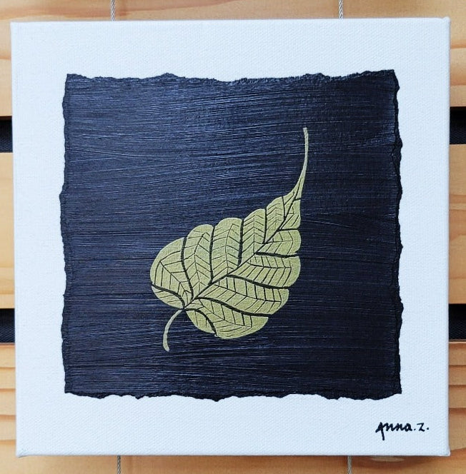 Intricate metallic block print of a leaf embossed on a black background. Deep gold colored embossing on black cardstock and white canvas.