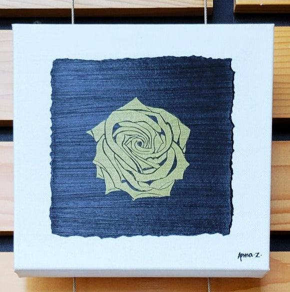 Intricate metallic block print of a rose embossed on a black background. Deep gold colored embossing on black cardstock and white canvas.