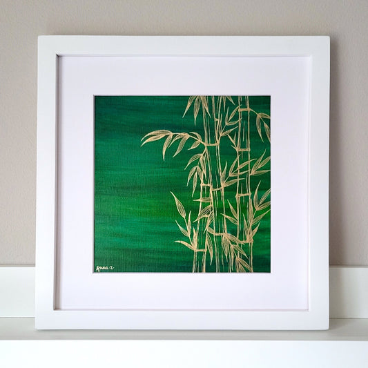 Stylized drawing of bamboo leaves and branches in gold ink against a deep green watercolor background, balancing richness and minimalism. Artwork is in a white wooden frame.