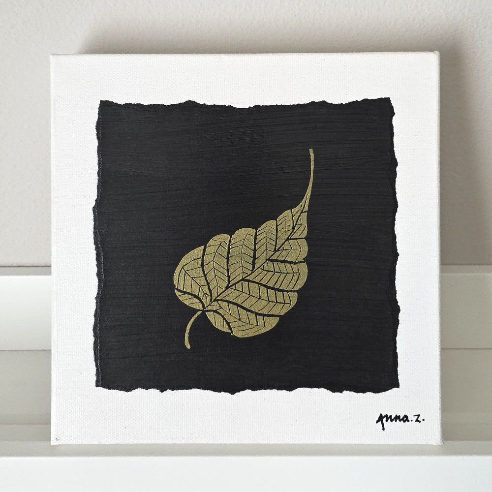 Intricate metallic block print of a leaf embossed on a black background. Deep gold colored embossing on black cardstock and white canvas.