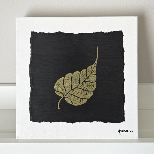 Intricate metallic block print of a leaf embossed on a black background. Deep gold colored embossing on black cardstock and white canvas.