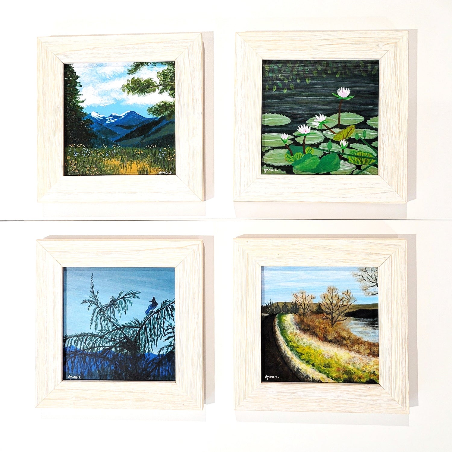 Four miniature landscape paintings in white wooden frames