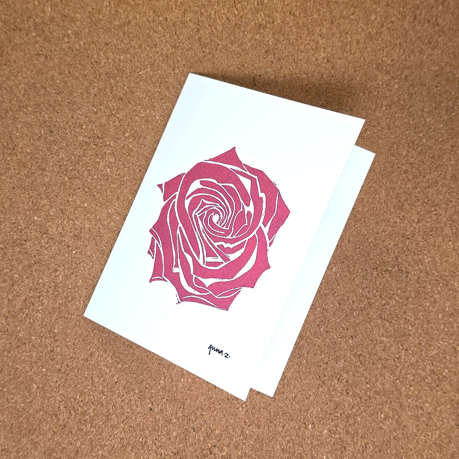Notecard featuring a digital print reproduction of an original hand-carved block print artwork of a rose in red on a white background.