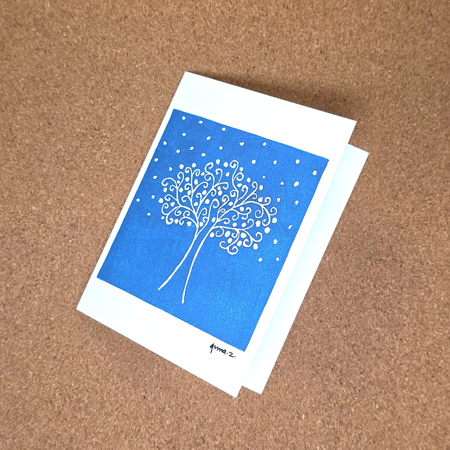 Notecard featuring a digital print reproduction of an original hand-carved block print artwork of a tree with swirly branches against a starry sky. Blue and white artwork.
