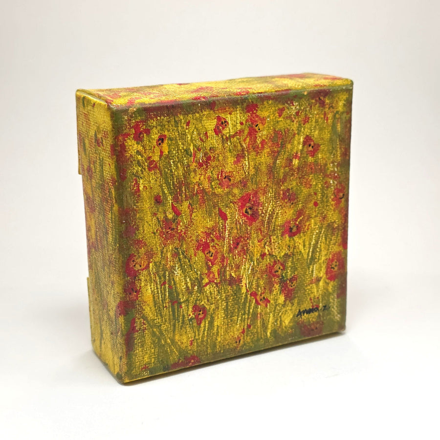 Angled side view of a mini painting of bright colored poppies in the glow of the summer sun. A warm grassy meadow completes the atmosphere of this dreamy mini painting in an abstract style.