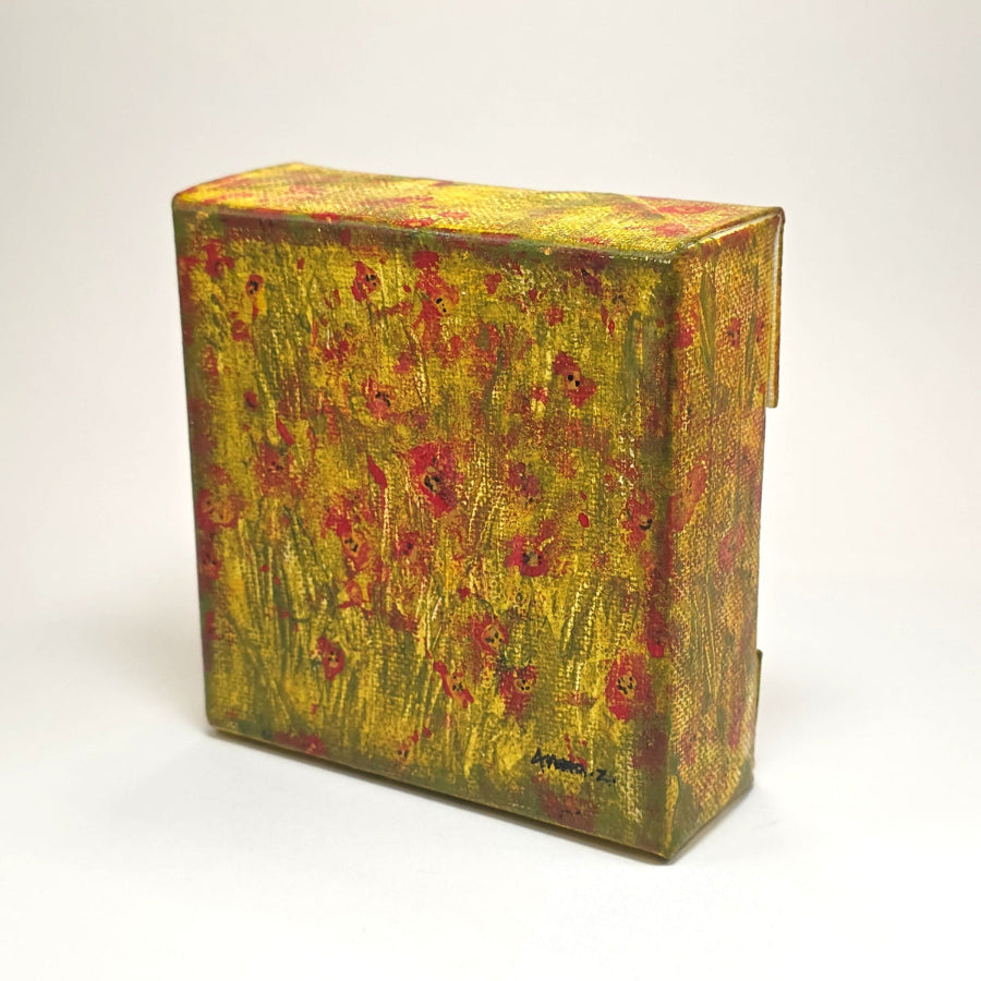 Angled side view of a mini painting of bright colored poppies in the glow of the summer sun. A warm grassy meadow completes the atmosphere of this dreamy mini painting in an abstract style.