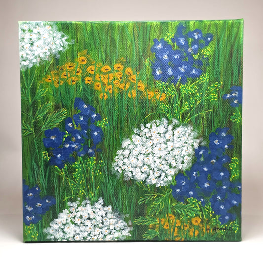 Front view of canvas painting of a whimsical scene of peaceful, happy wildflowers in blue, white and yellow against a grassy meadow. 