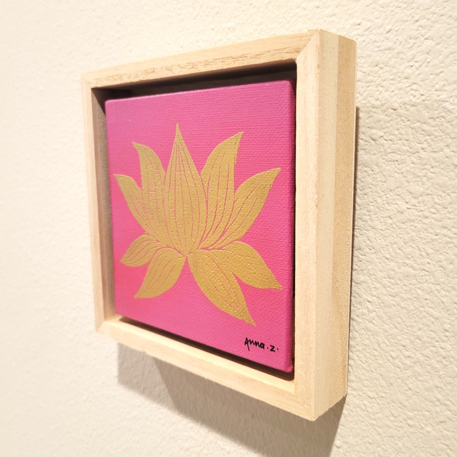 Golden lotus blossom set against a bright pink background on a framed mini-sized canvas panel. Metallic gold colored heat embossing from original carved block design, over an acrylic painted background.  Mounted in floater frame style within a 5" x 5" rustic wooden box frame with mini sawtooth hanger on reverse. The golden petals are perfectly complemented by the light colored wooden frame. 