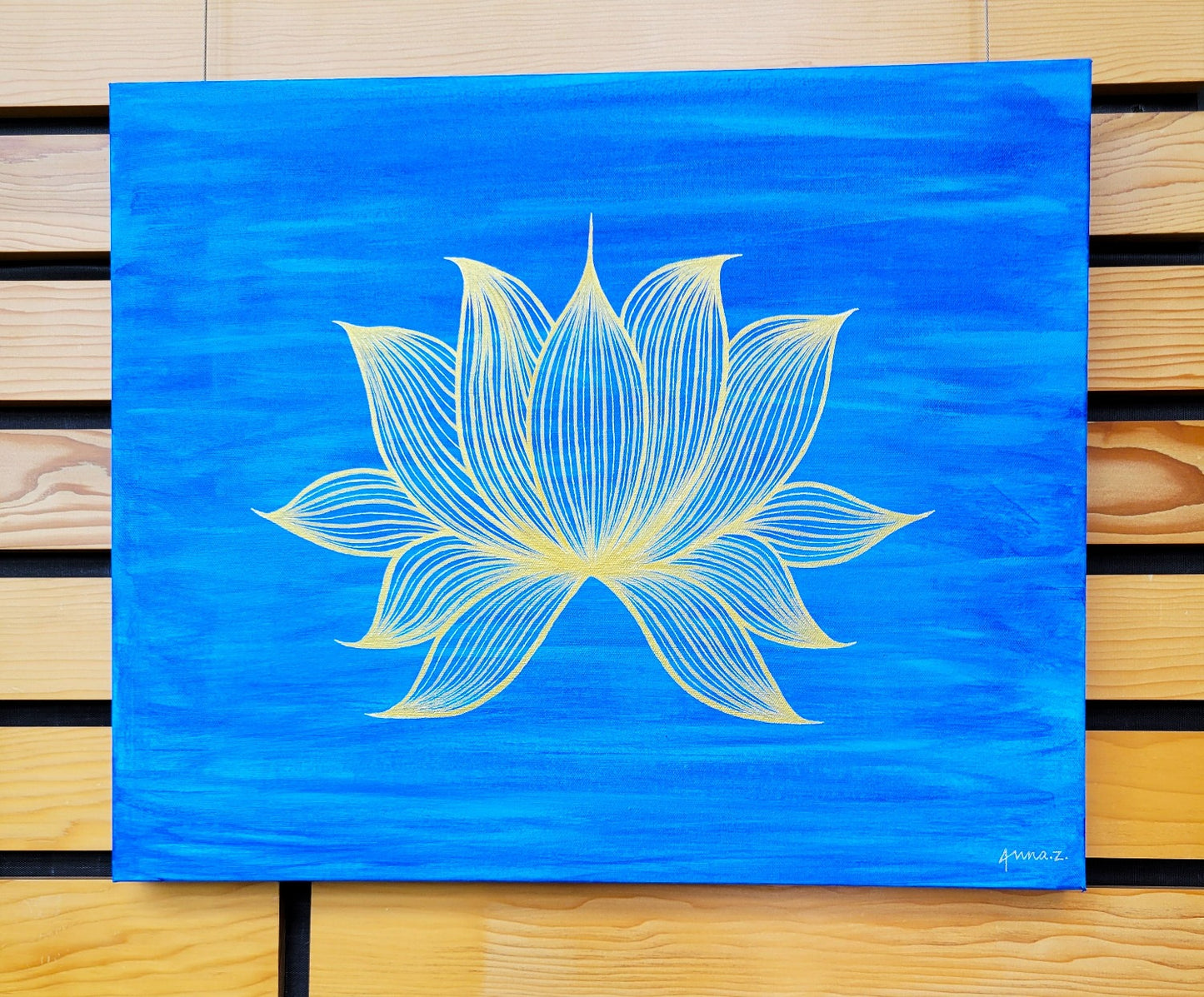 A painting of a stylized golden lotus blossom floats on bright blue water with ripples of reflected light.