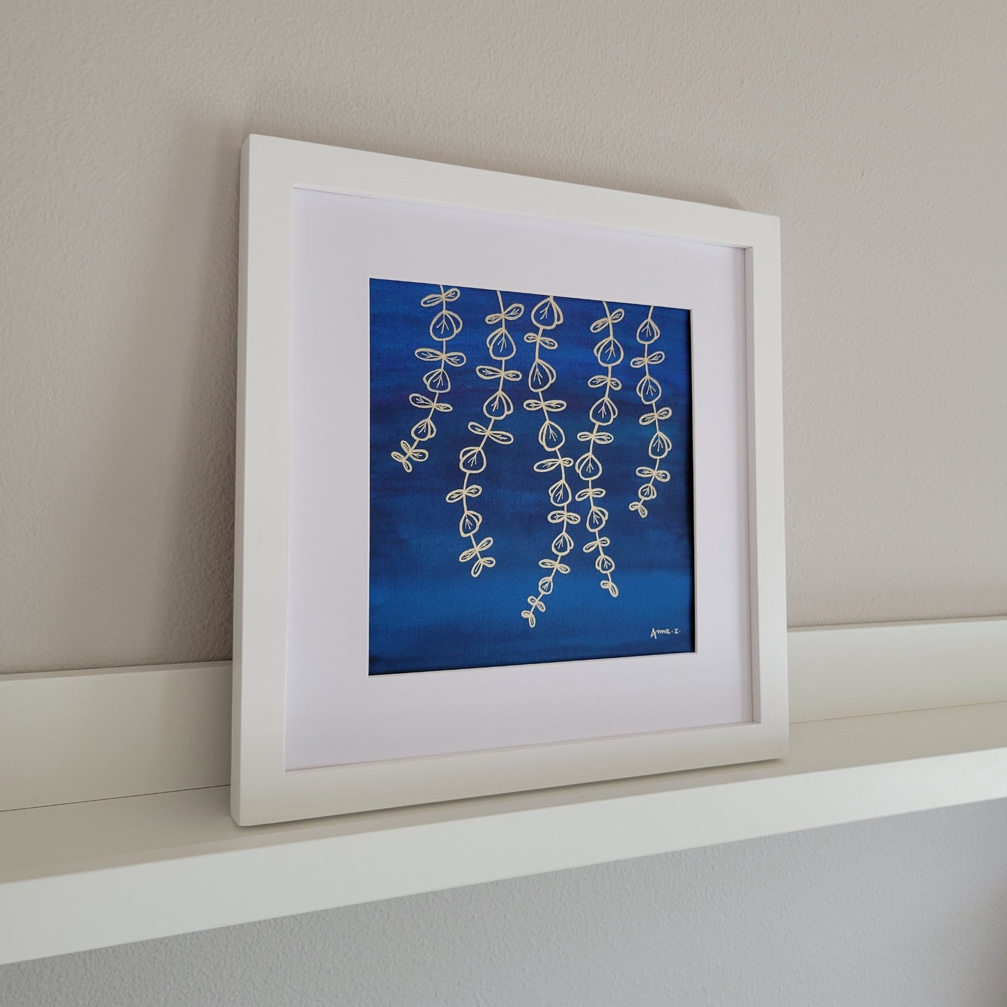 Golden leafy tendrils hanging in the breeze, with some veining detail on the oval leaves. In metallic ink set against a deep blue watercolor background with hints of green, this color combination creates a perfect balance of richness and minimalism. This piece has exactly 100 leaves, either fully or partially visible.