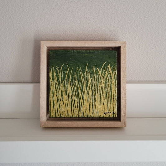 Golden blades of grass set against a deep moss green background on a framed mini-sized canvas panel. Metallic gold colored paint over acrylic. Mounted in floater frame style within a 5" x 5" rustic wooden box frame with mini sawtooth hanger on reverse. The golden grass catches daylight beautifully and is perfectly complemented by the light colored wooden frame. 