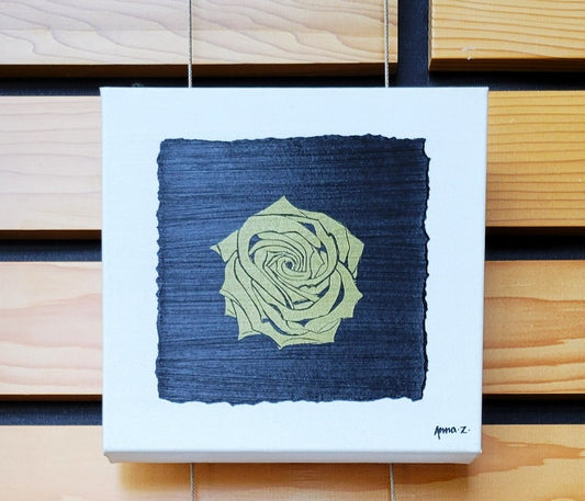 Intricate metallic block print of a rose embossed on a black background. Deep gold colored embossing on black cardstock and white canvas.