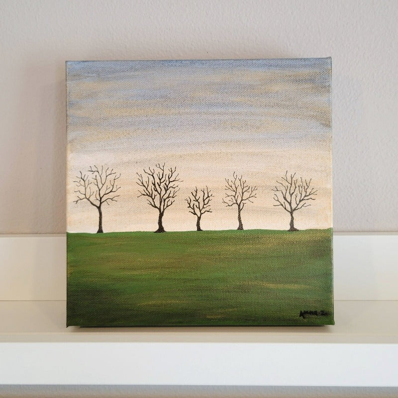 A dreamy landscape of bare trees against a golden twilight horizon and deep green fields. Subtle metallic highlights add interest and atmosphere.